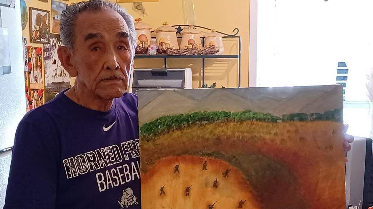 Paul Vasquez holds his painting of a Korean War battle scene from Christmas Day 1951.
