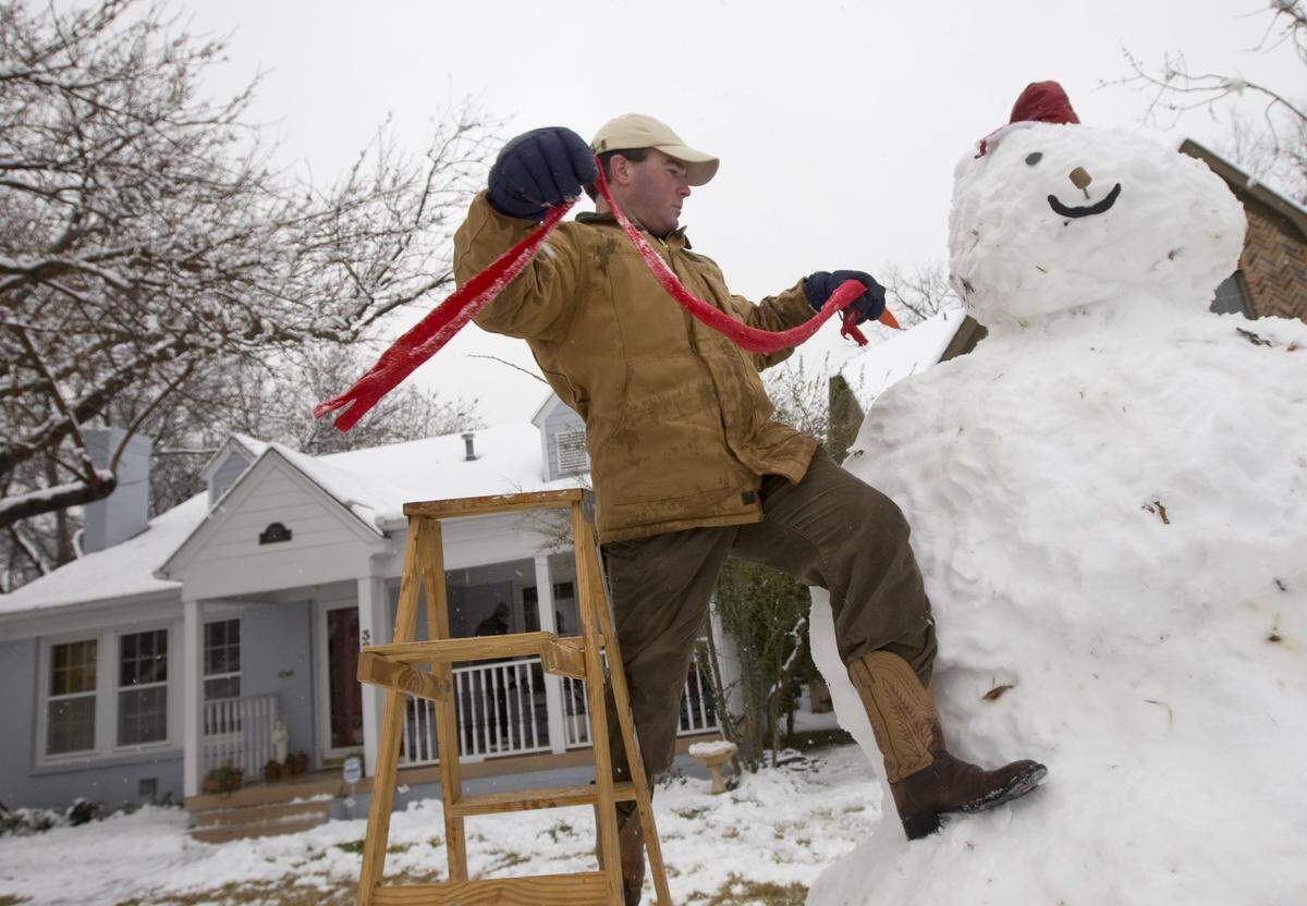 Sherman Jones, 35, puts the finishing touches on a gigantic snowman built by several families in the west-side Fort Worth neighborhood during the snow fall on Thursday, February 11, 2010.
