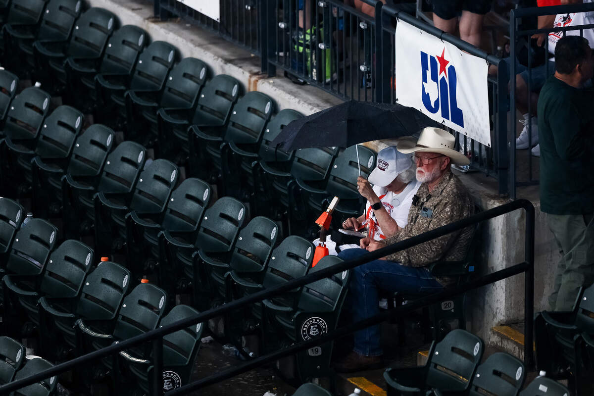 Fans sit in the rain during the UIL Texas high school baseball state championships at Dell Diamond in Round Rock, Texas, on Friday. June 5, 2026.