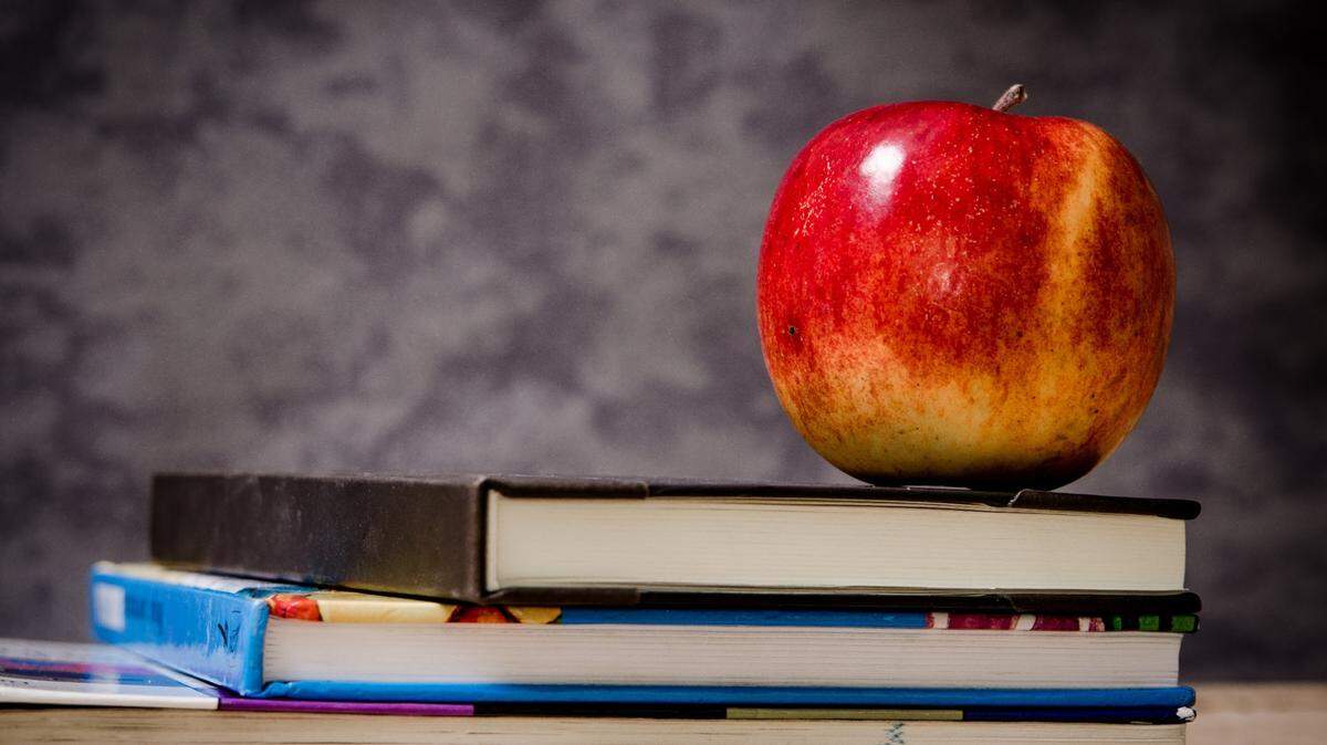 School books and apple in a classroom.