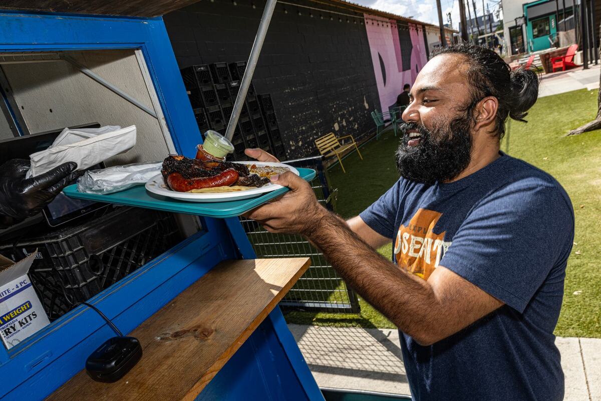 Fort Worth resident Amin Nayem receives his plate of barbecue from Sabar BBQ at Fort Worth on Saturday, Aug. 31, 2024.