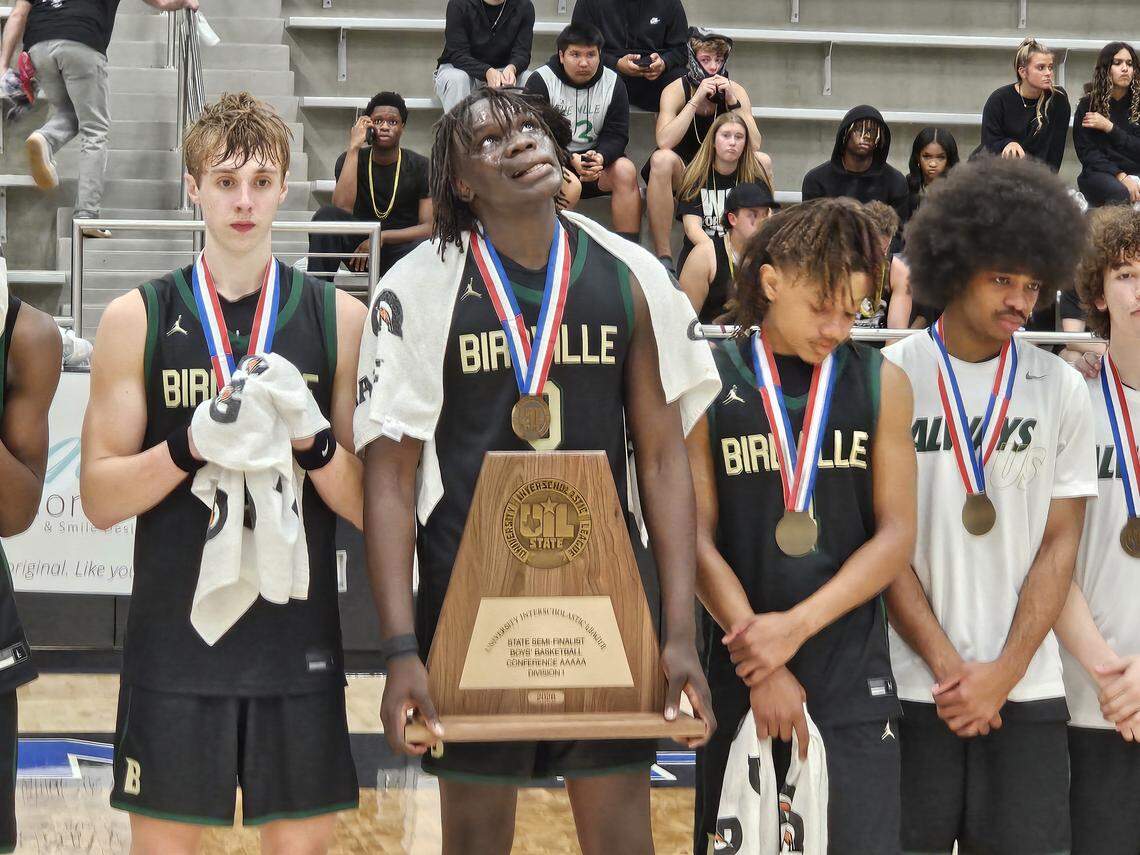 Birdville’s Gabriel Zachariah holds the state semifinalist trophy and stands with teammates to get medals after the Hawks were defeated by Frisco Heritage 65-63 in a Class 5A Division I state semifinal on Tuesday at Hebron High School in Carrollton.