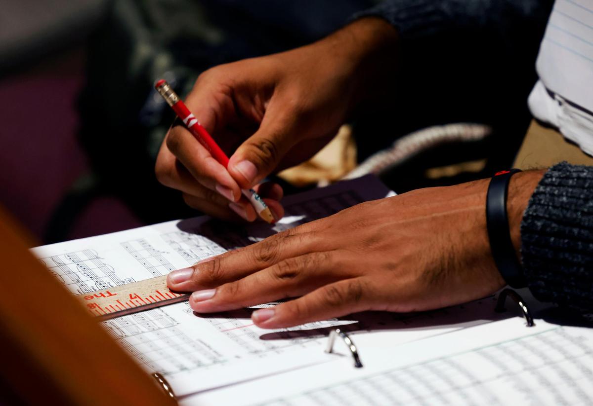 Assistant conductor Christian Bernard marks measure lines while preparing during rehearsal on Thursday, Nov. 21, 2024, at First Methodist Mansfield.