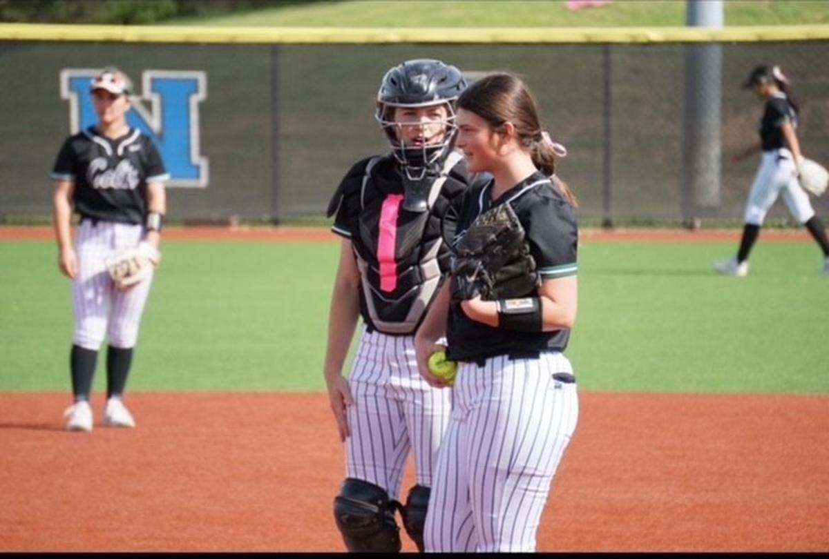 Arlington High catcher Abby Moore converses with pitcher Tatum Pacos. Moore made the switch to softball as a senior after playing baseball for many years.