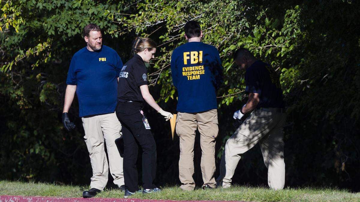 Police officers and FBI agents collect evidence behind Utah Valley University as they investigate the shooting of political activist Charlie Kirk on Sept. 11, 2025, in Orem, Utah.