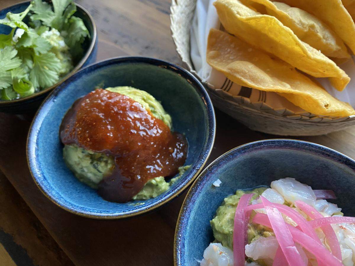 The guacamole trio at Tinie’s includes guac with chipotle-bacon jam (center) and red onion-shrimp (right).