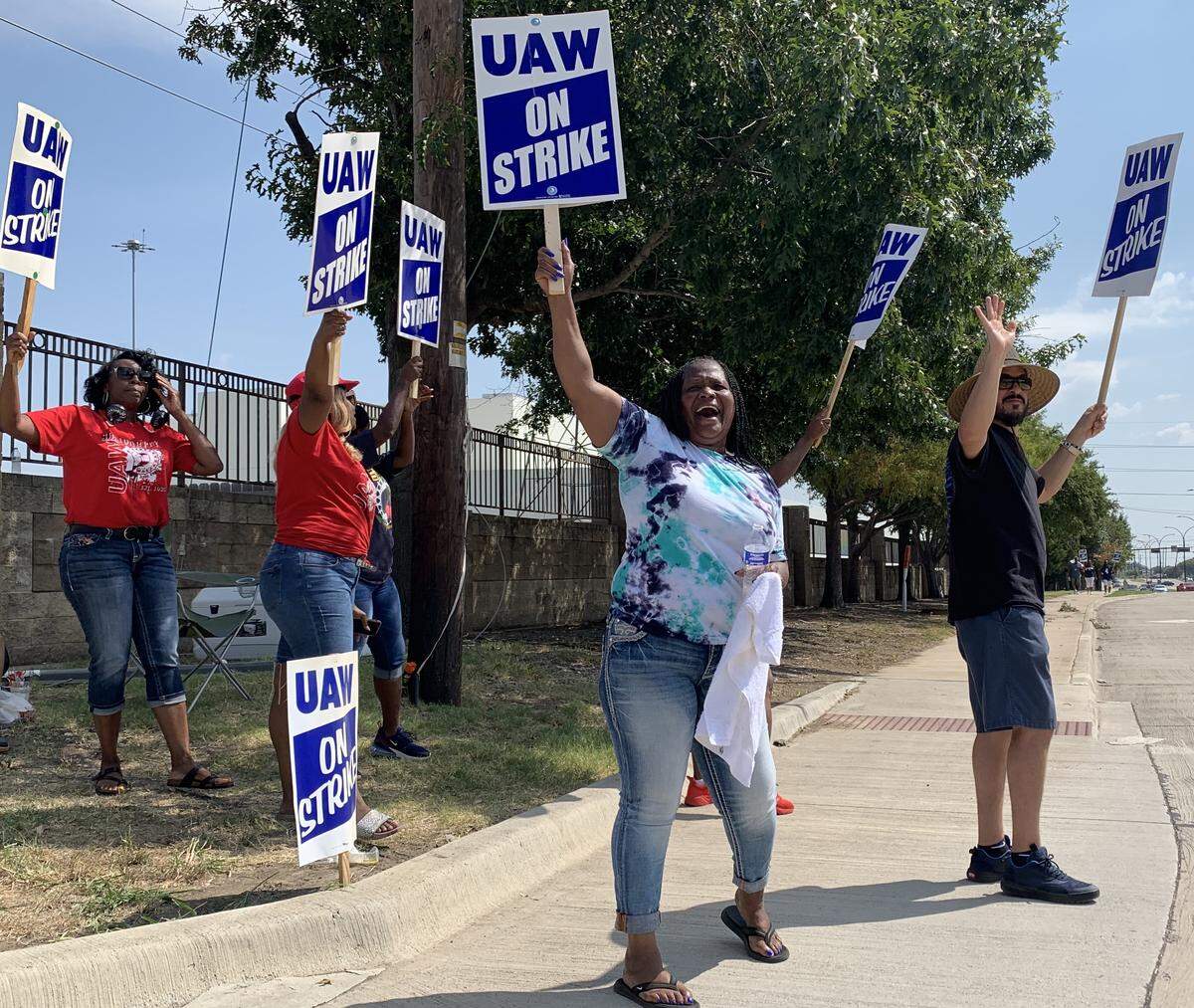 Lisa Anderson (center) and co-workers wave and chant unifying slogans as motorists pass the General Motors plant in Arlington in 2019.