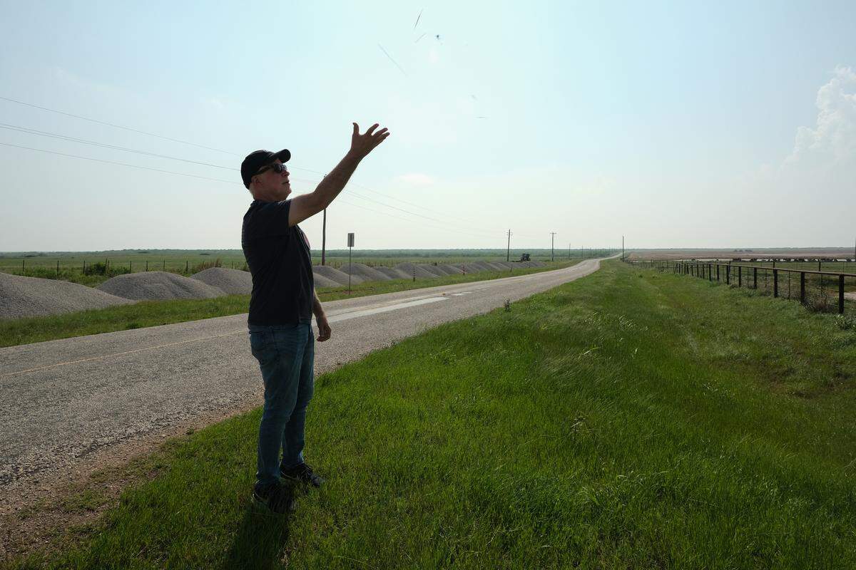 Storm chaser Martin Lisius threw a piece of grass into the air to test the speed and direction of the wind while watching thunderclouds form near Iowa Park, Texas, on April 26, 2026.
