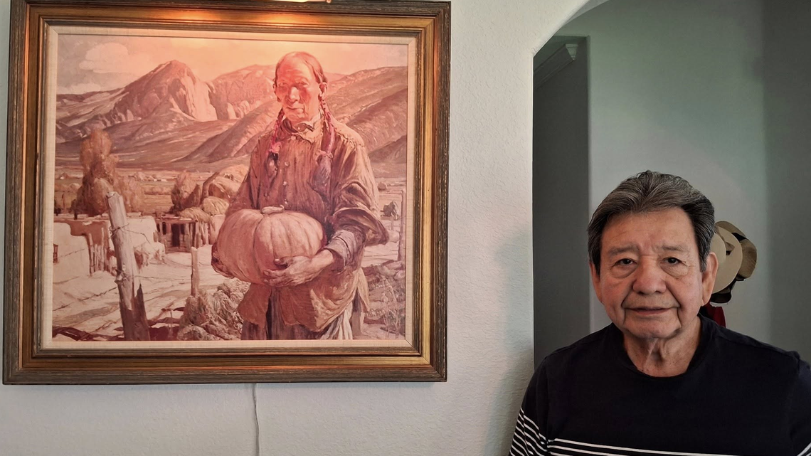 Former North Side High School Principal Mauro Serrano stands next to his print copy of the October-Taos painting hanging in his home.