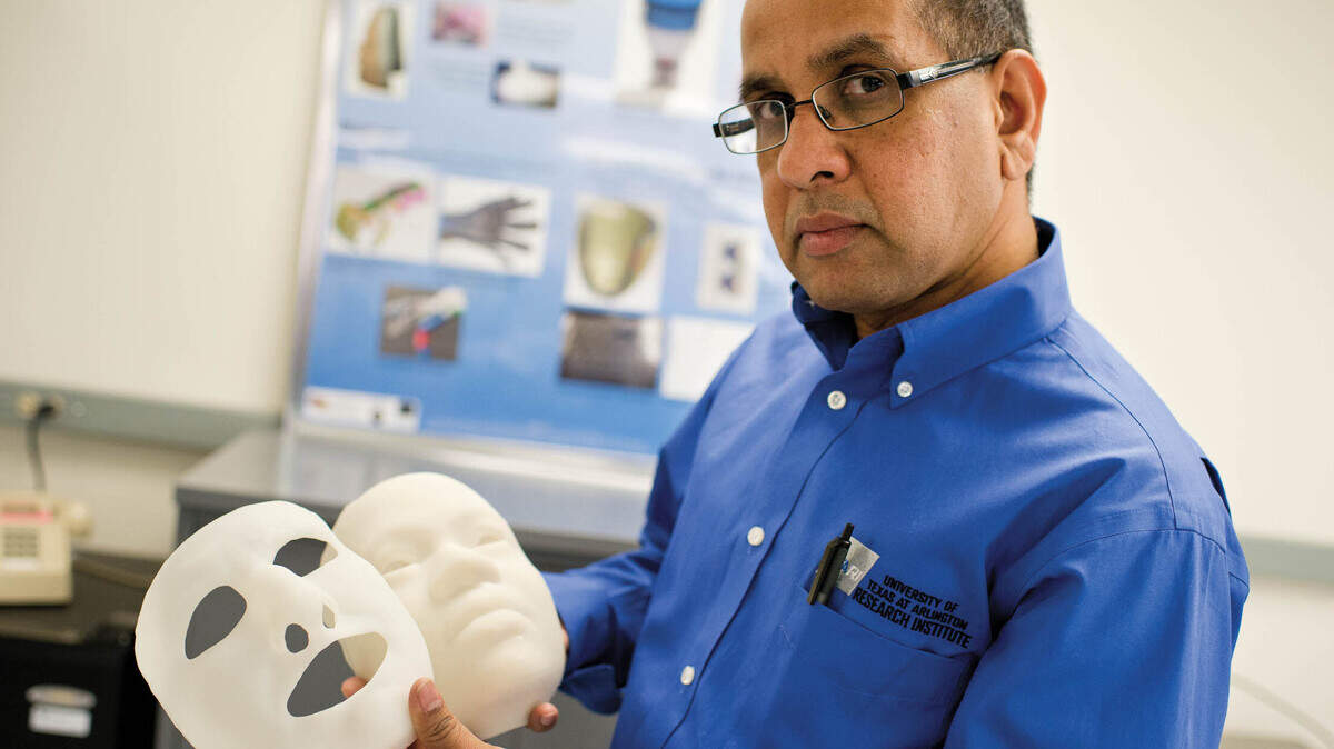 Muthu Wijesundara holding facial models in a research lab at UTA’s Research Institute.