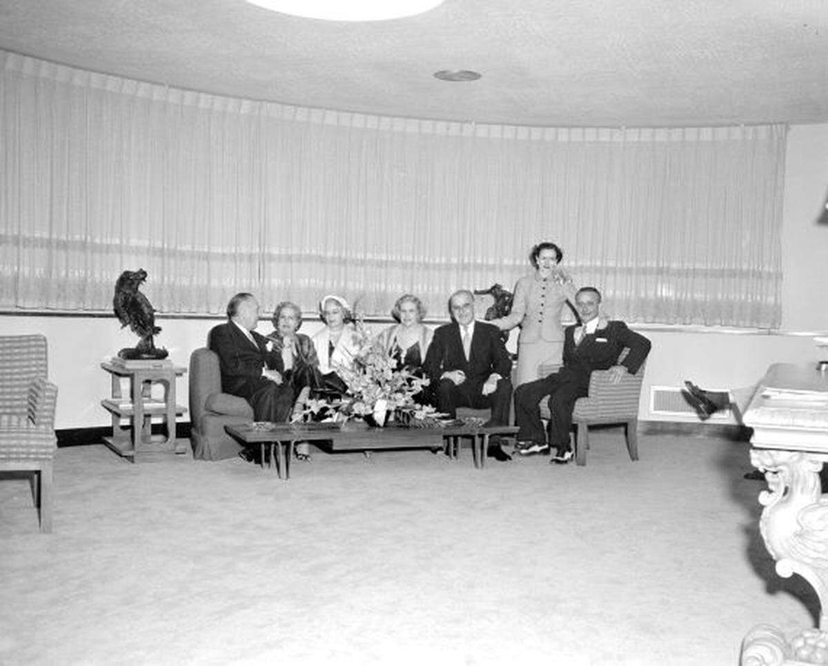 The group is seated and smiling on a couch in a posh lounge at the airport.