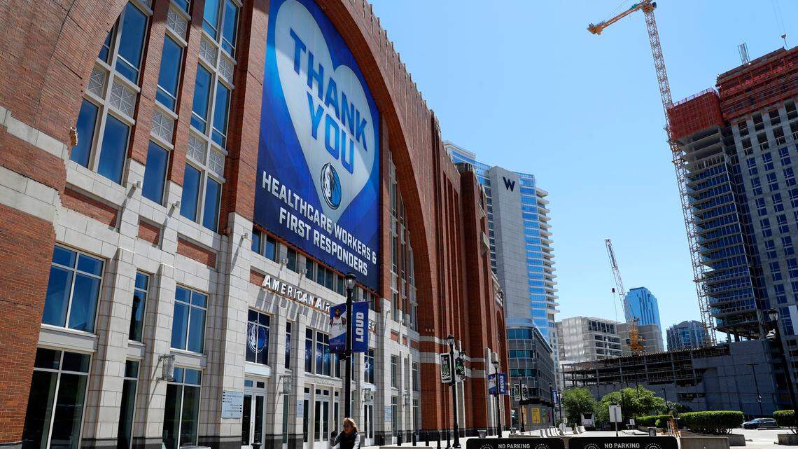 A person on a bike rides past a large banner hanging outside American Airlines Center, home of the Dallas Mavericks and the Dallas Stars, in Dallas, Thursday, April 16, 2020. The banner, which has a Mavericks logo on it, thanks first responders and healthcare workers during the COVID-19 crisis. (AP Photo/Tony Gutierrez)