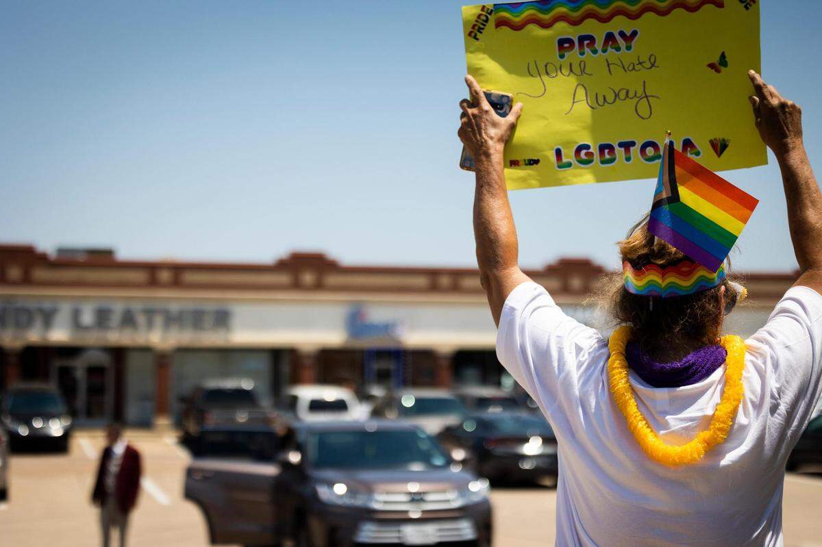 A protester holds up a sign as church members arrive for service at Stedfast Baptist Church on July 24, 2022, in Watauga. People driving by honk in support as well as dropping off supplies such as water and food for the protesters.