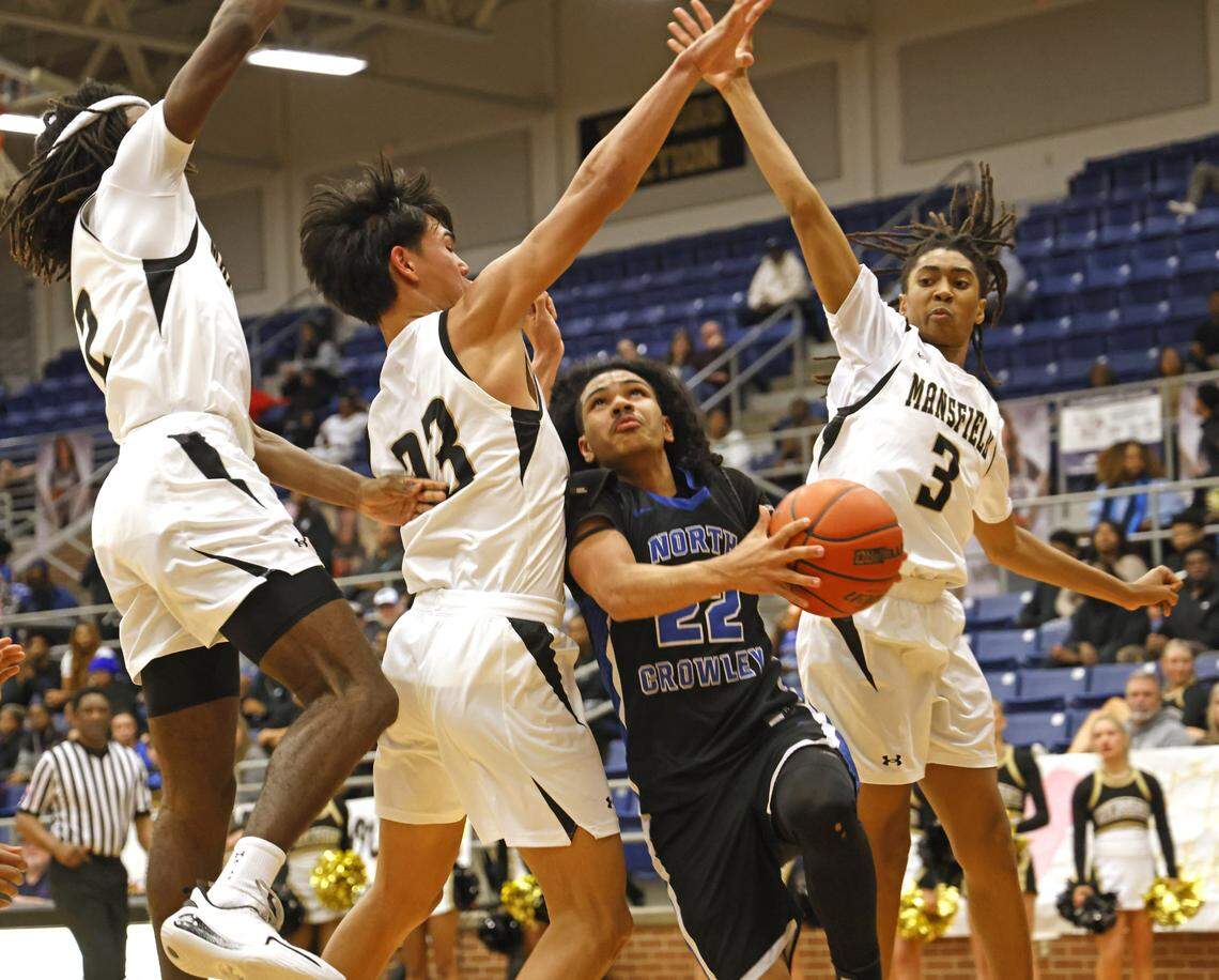 North Crowley guard Isaak Hayes (22) gets two the hard way defended by Mansfield's Caden Shaver (23) and KT Turner (3) during the first half of a UIL boys basketball game between North Crowley and Mansfield at Mansfield High School in Mansfield, Texas, Tuesday Jan. 20, 2026