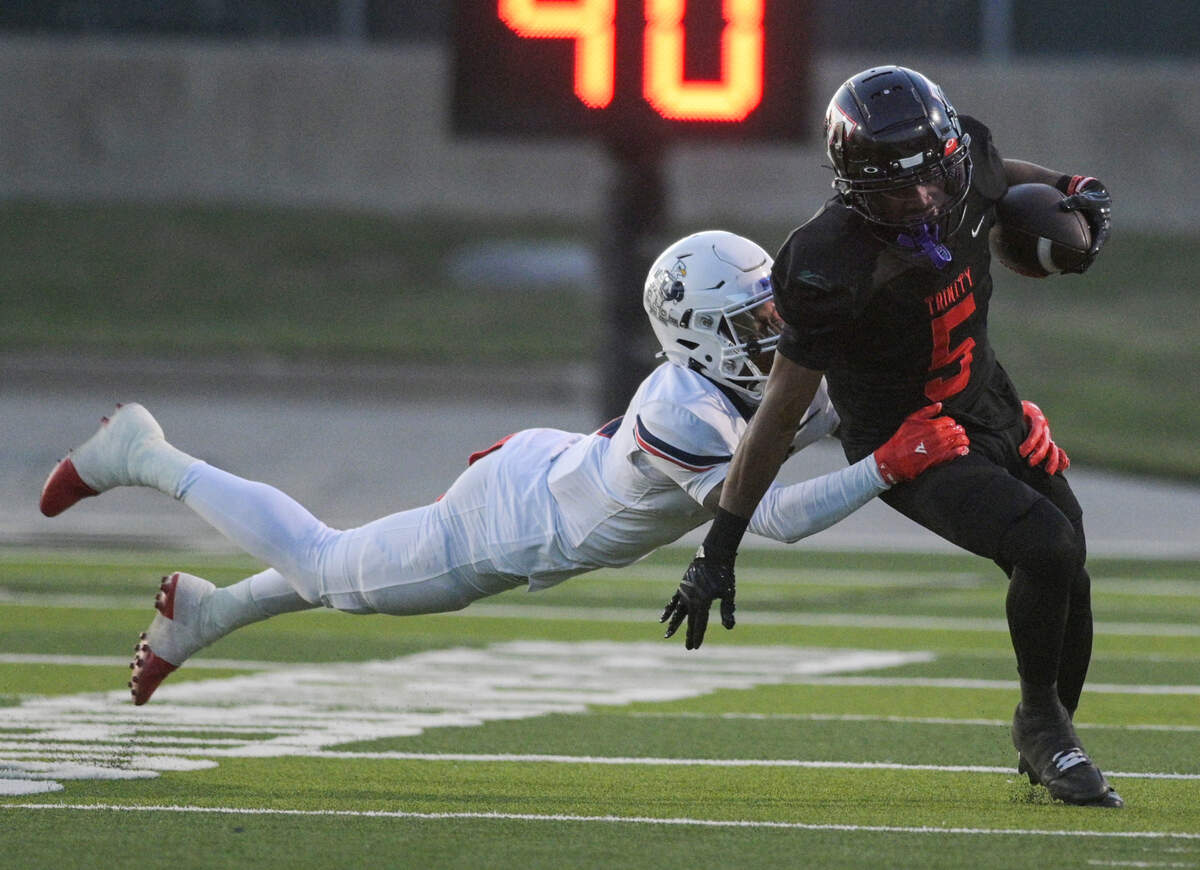 Trinity Trojan running back Ethan Williams-Wright (5) runs down the field as Allen Eagle Kai Wheaton (5) dives for the tackle during a UIL football playoff game against Allen High School at Dragon Stadium in Southlake, Texas on Friday, Nov. 29, 2024.