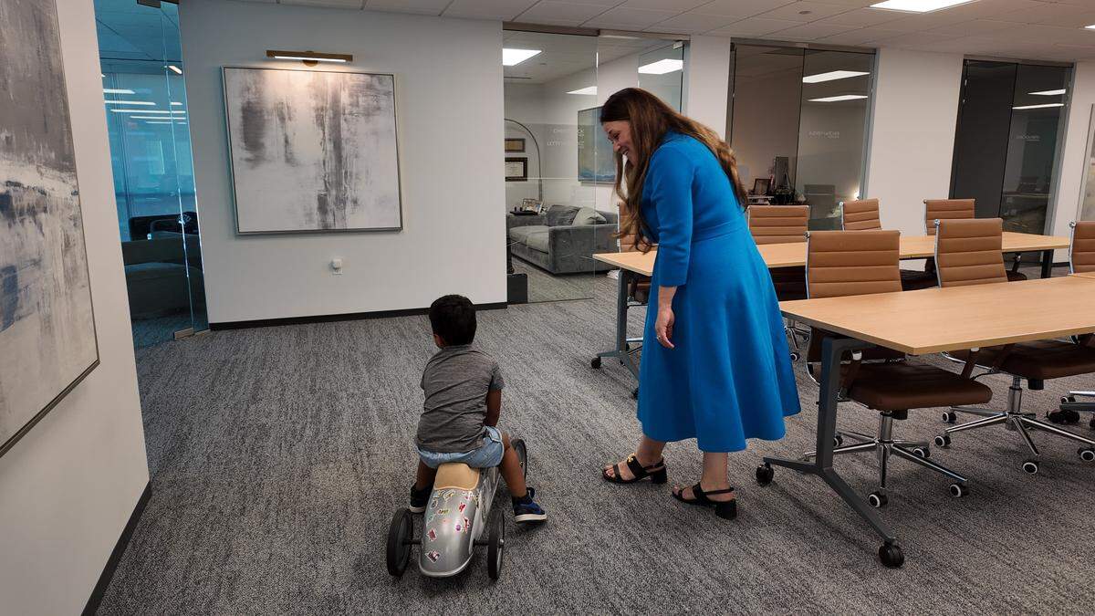 Anna Summersett walks alongside her son Case, 3, as he rides his silver race car at Varghese Summersett law firm in downtown Fort Worth on Oct. 15, 2025.