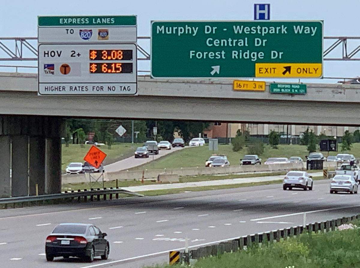 Motorists drive past a TEXPress lanes sign advertising tolls for $6.15 for a 5.7-mile trip.