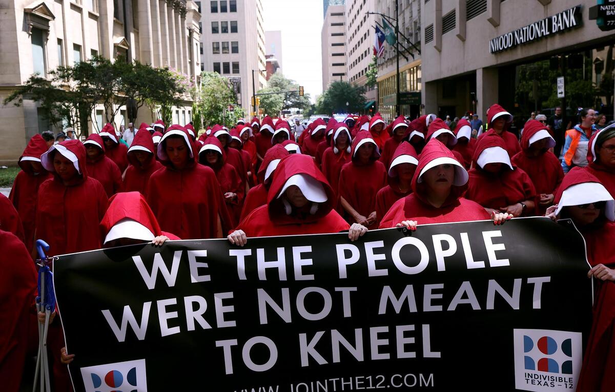 Protesters dressed in Handmaids outfits march in downtown Fort Worth in the March of Dissent hosted by Indivisible 12 on June 14, 2025.