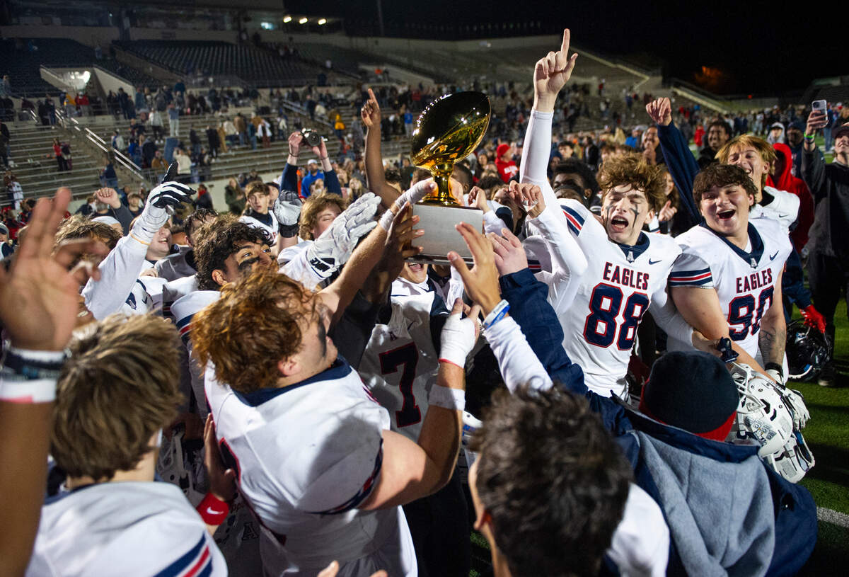 Allen players celebrate lifting a trophy after winning the UIL 6A-D1 regional semifinal game against Euless Trinity High School at Dragon Stadium in Southlake, Texas on Friday, Nov. 29, 2024.