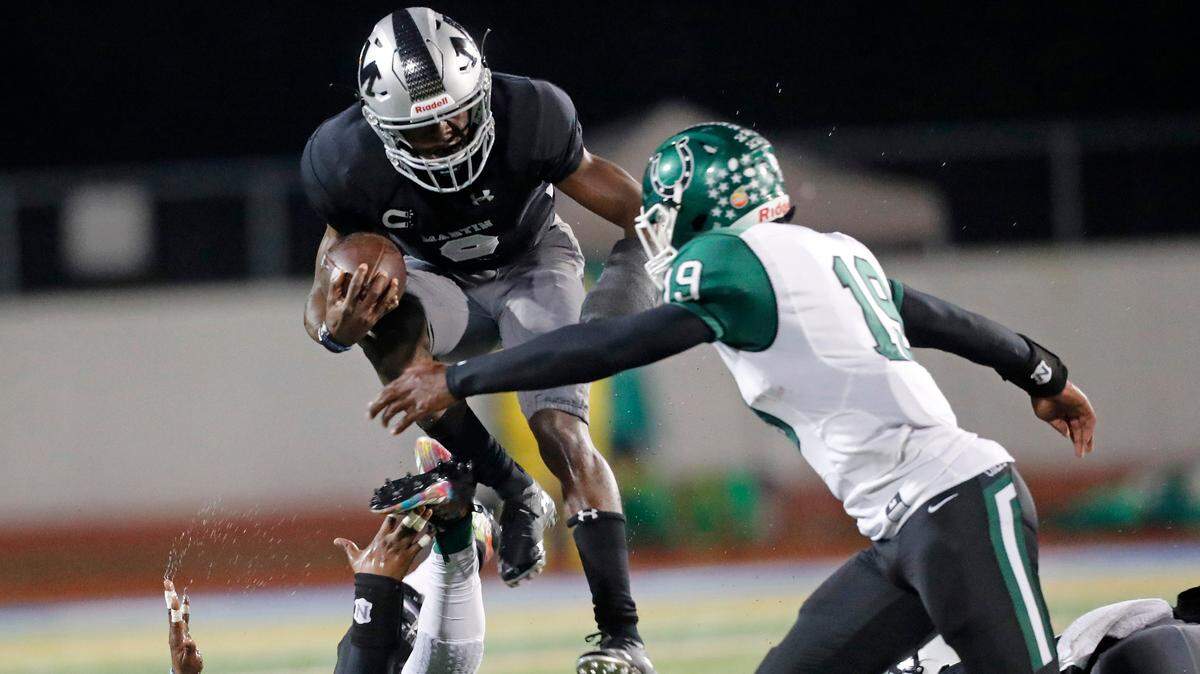 Martin quarterback Willie Roberts (3) jumps over Arlington linebacker ‘s Ladarian Perry (26) and  A’Tavion McDonald (19)during the first half of a high school football game at UTA Maverick Stadium Friday, Oct. 19, 2018. Martin led 18-14 at the half. (Special to the Star-Telegram Bob Booth)

