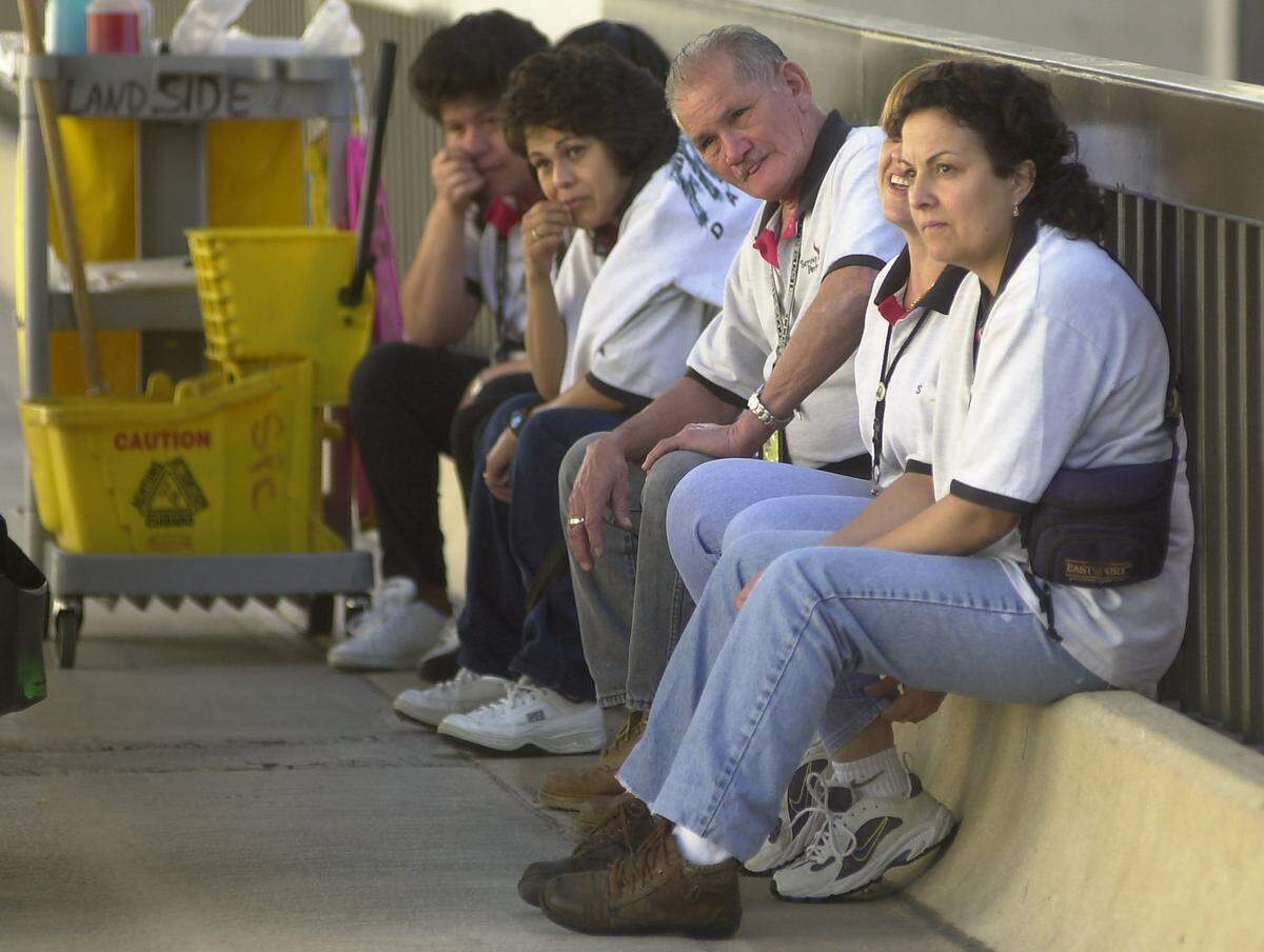 Cleaning crews sit waiting outside DFW Airport's Terminal C while a security sweep was in progress inside on Sept. 12, 2001.