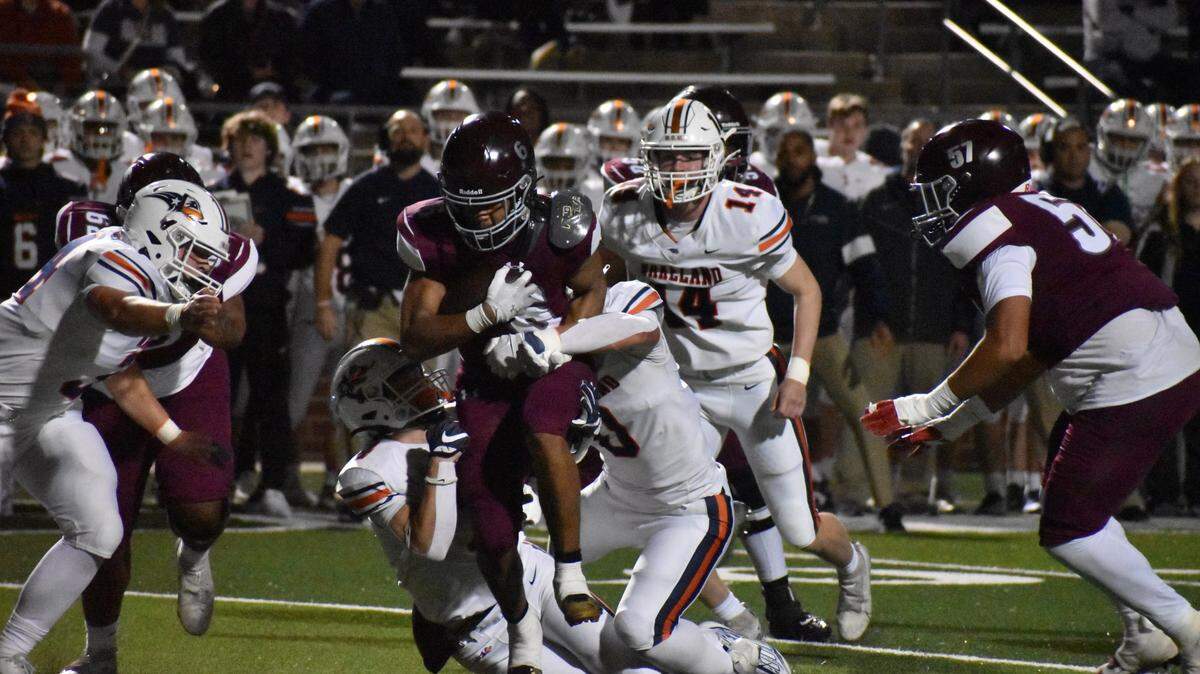 Mansfield Timberview’s Jaylon Woods drives through the tackle of two Frisco Wakeland defenders during Friday’s game.