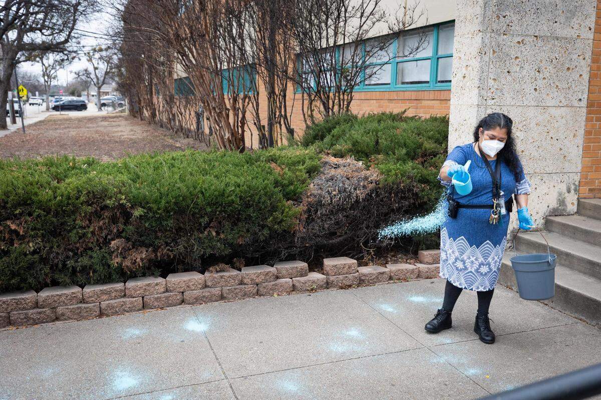 Herminia Armijo pours salt on the walkways in preparation for the winter storm Wednesday, Feb. 2, 2022, at Worth Heights Elementary in Fort Worth.