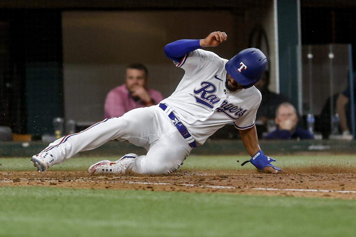 Rangers shortstop Marcus Semien slides into home plate on March 30, 2023, at Globe Life Field in Arlington. The Texas Rangers beat the Philadelphia Phillies 11-7.