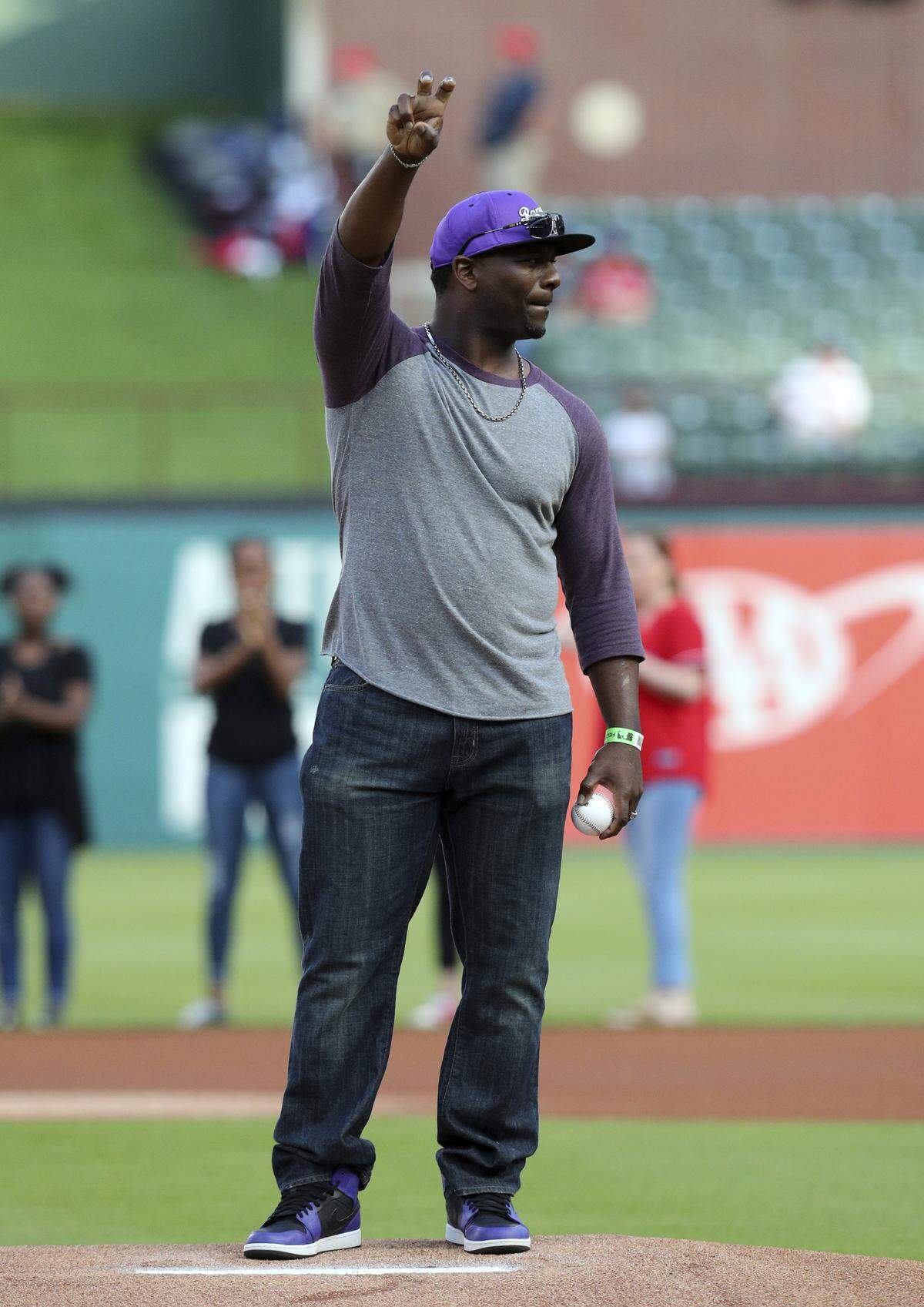 Pro Football Hall of Fame running back and former TCU player LaDainian Tomlinson makes the university's Horned Frog sign before throwing out the ceremonial first pitch before a Rangers' game in May.
