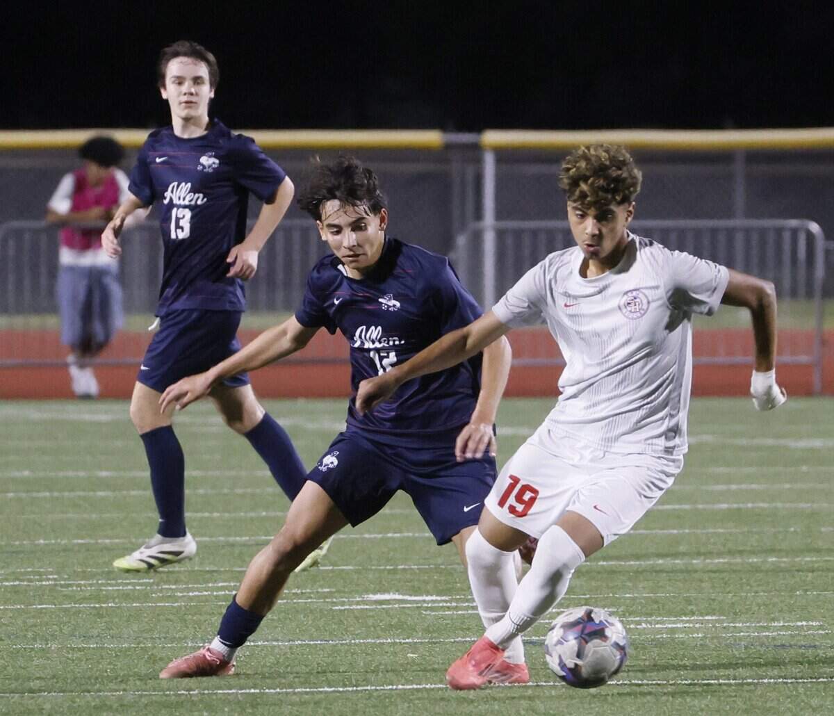 Arlington Sam Houston Edgar Vasquez (19) brings the ball down the pitch in front of Allen midfielder Joao Nunes (12) during the first half of a UIL area round boys soccer playoff game at Tommy Standridge Stadium in Carrollton, Texas, Tuesday, March 24, 2026.