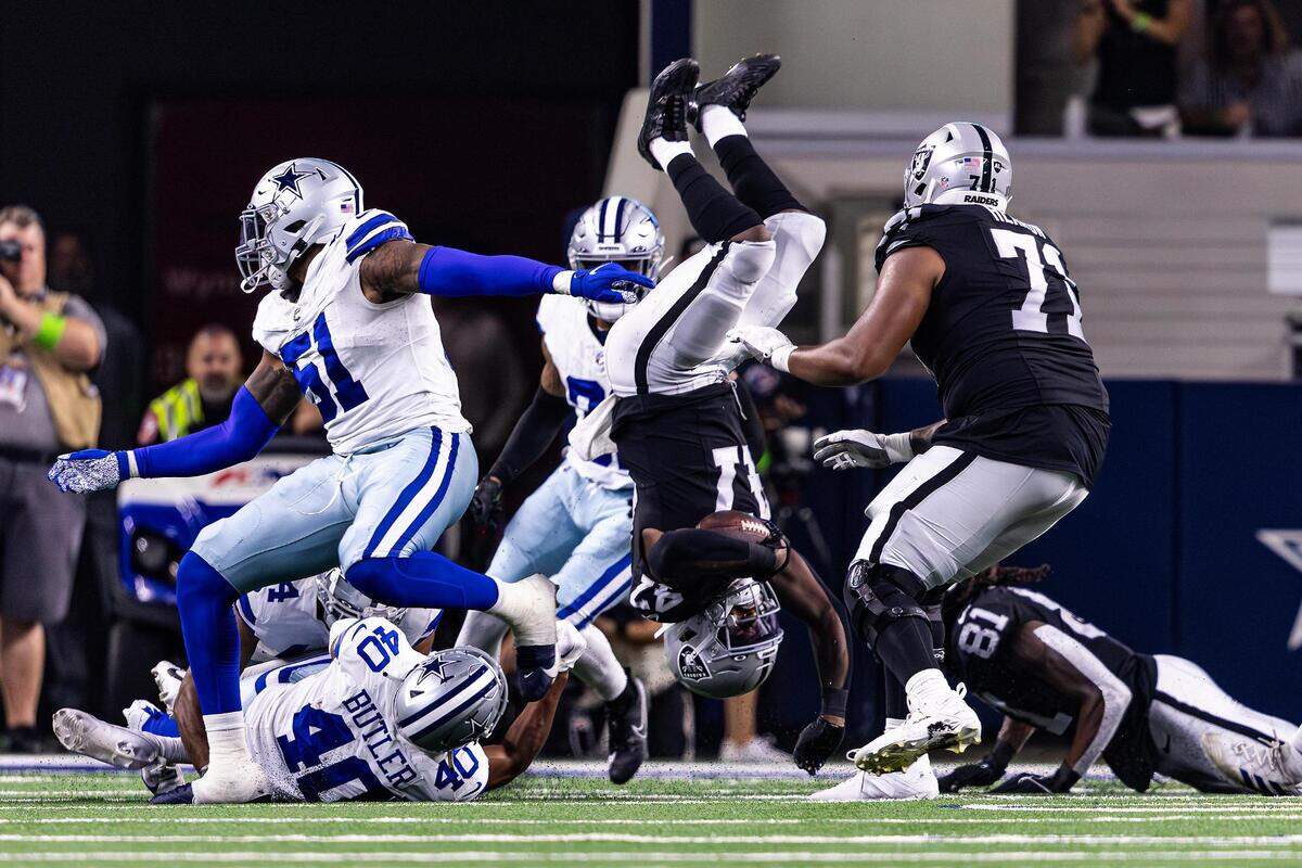 Las Vegas Raiders running back Sincere McCormick (47) gets flipped over by Dallas Cowboys defenders in the second half of a preseason game against the Las Vegas Raiders at AT&T Stadium in Arlington, Texas on Saturday, Aug. 26, 2023.