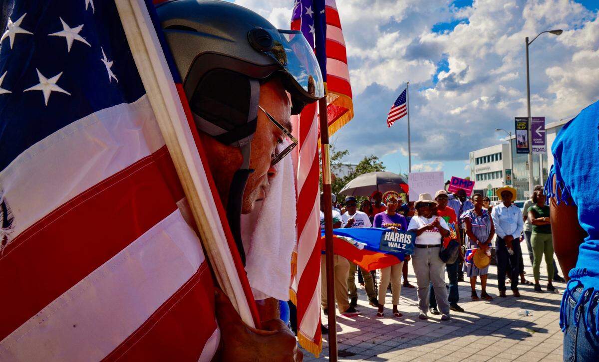 North Miami resident Frandzy Bruce Bernadin, left, wipes the sweat of his brow as he watches members of South Florida’s Haitian community as the Miami-Dade Democratic Haitian Caucus hosted a rally against former President Donald Trump and running mate JD Vance on Sunday, September 22, 2024, in North Miami, Florida.