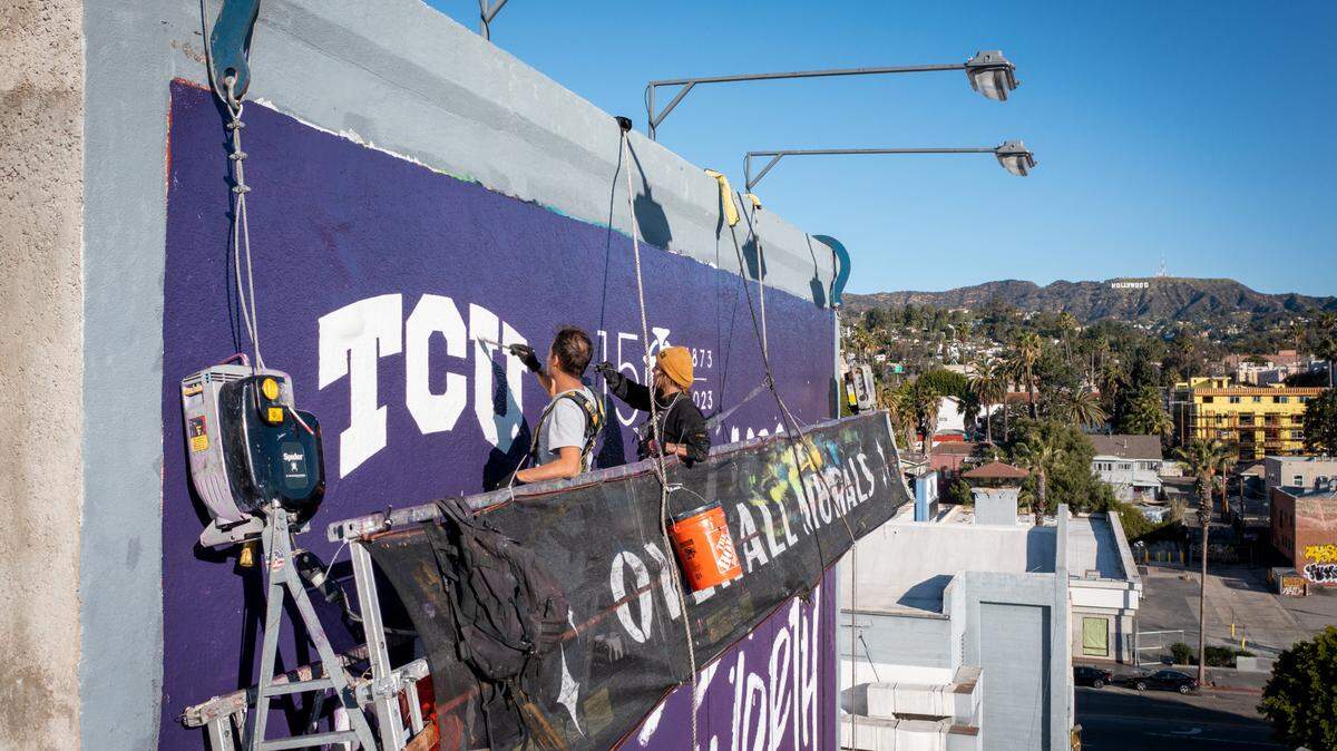 Workers put up a TCU mural in Los Angeles, one of several nationwide to help celebrate the school’s 150th anniversary and as part of the university’s Lead On program.