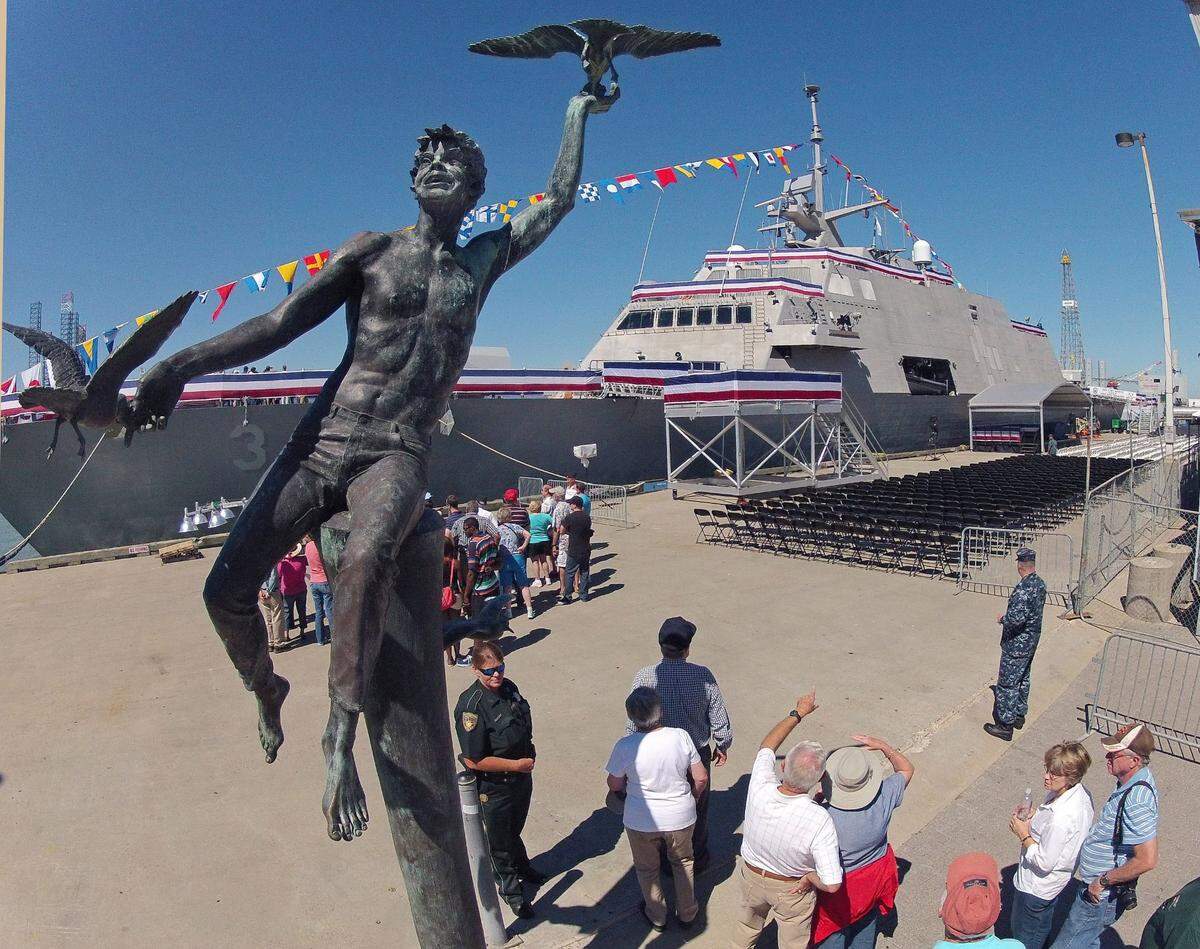 A statue of a boy playing with seagulls stands above tourists gathering for a tour of the USS Fort Worth in Galveston on Sept. 20, 2012.
