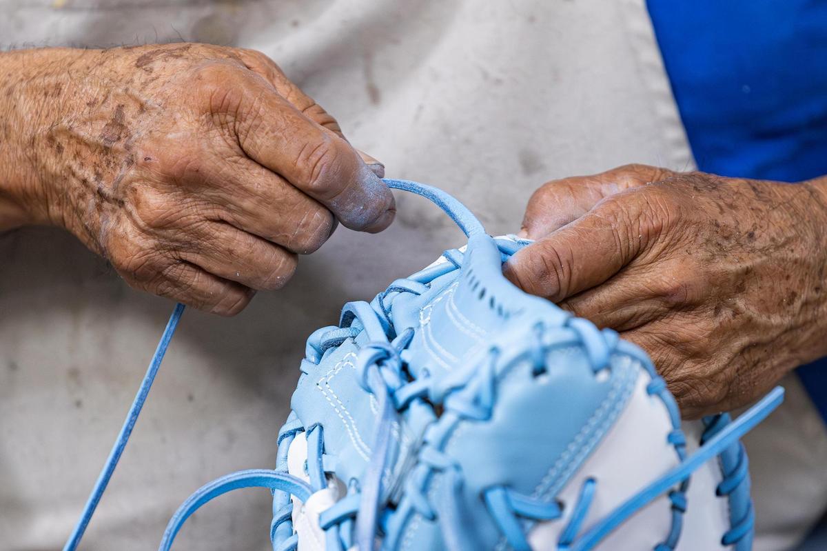 Pedro Castro Suarez ties the strings of a glove at the Nokona glove factory.