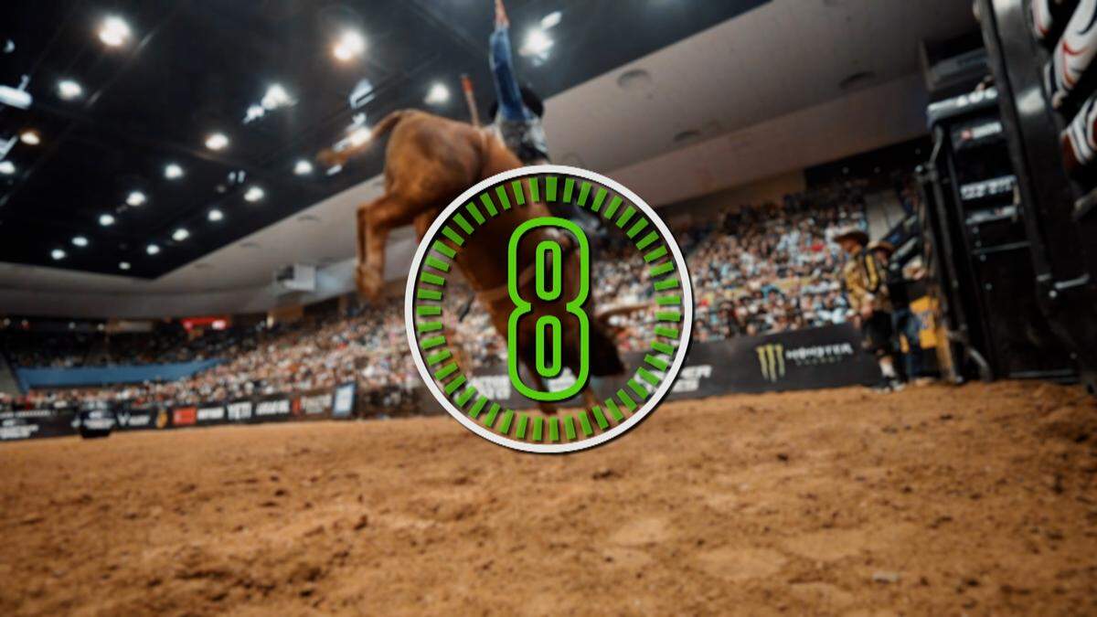 A bull rider attempts to stay on the bull as it bucks.