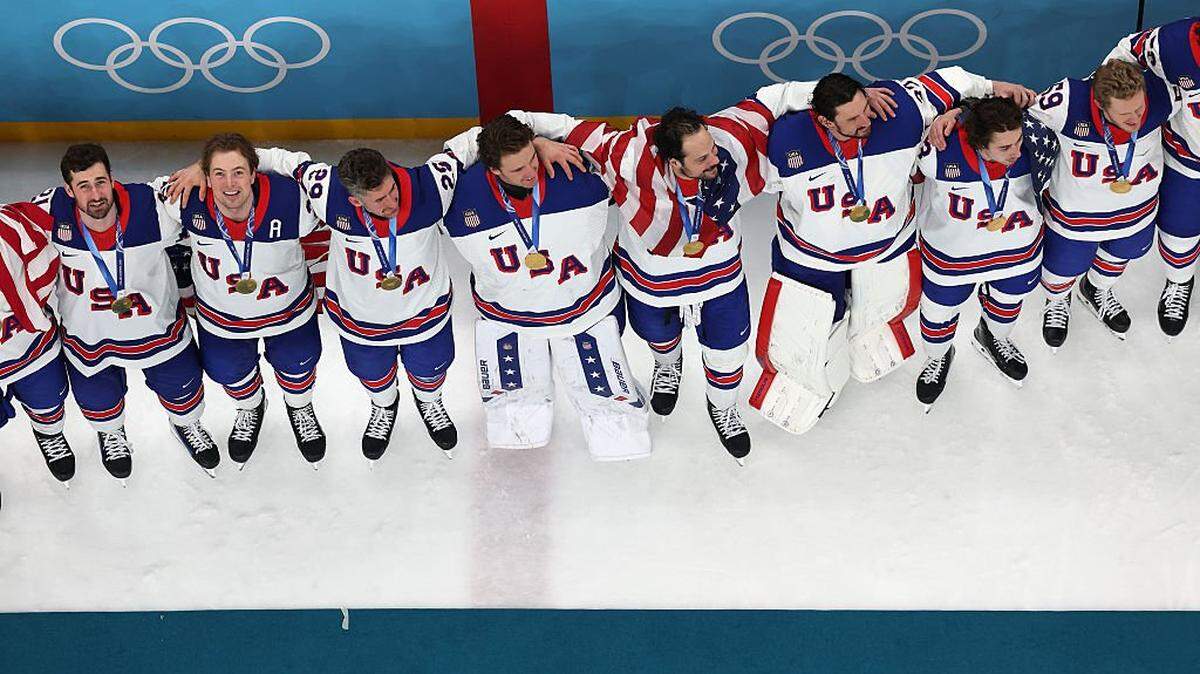 MILAN, ITALY - FEBRUARY 22: (EDITOR'S NOTE: Image was captured using a remote camera positioned above the field of play.) (L-R) Dylan Larkin #21, Charlie McAvoy #25, Brock Nelson #29, Jake Oettinger #30, Auston Matthews #34, Connor Hellebuyck #37, Quinn Hughes #43 and Jake Guentzel #59 of Team United States participate in the national anthem during the medal ceremony following the Men's Gold Medal match between Canada and the United States on day 16 of the Milano Cortina 2026 Winter Olympic games at Milano Santagiulia Ice Hockey Arena on February 22, 2026 in Milan, Italy. (Photo by Jared C. Tilton/Getty Images)