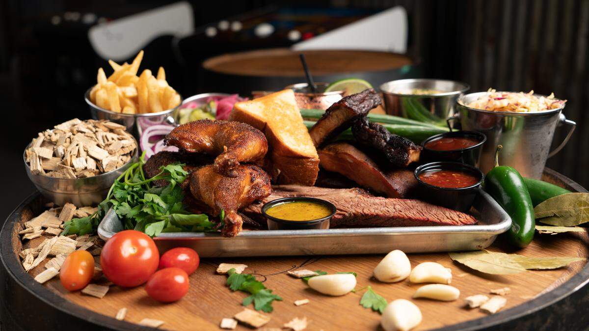 Three-meat plate (half smoked chicken, pork ribs, brisket) with smoked poblano creamed corn, jalapeño coleslaw, french fries and more at Barrel & Bones Craft Bar and Smokehouse, which opened in September in Montgomery Plaza in Fort Worth — in a spot where seven restaurants have come and gone in the past few years.