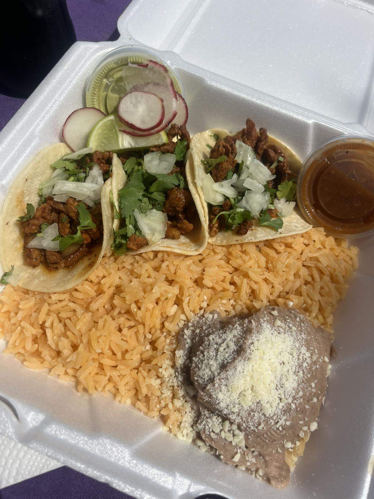 Three El Pastor tacos with rice and beans from Super Taco food truck in north Fort Worth. This food truck offer $1 taco Tuesdays.