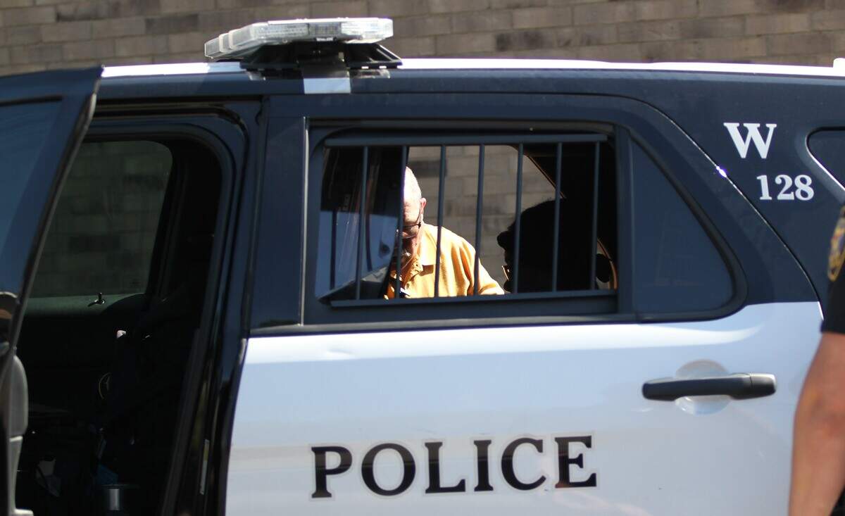 An unidentified woman who police say shot her husband after an argument over their tax return is interviewed by police in a patrol vehicle Thursday morning. Relatives said the woman will be taken to a women's shelter for her own safety.