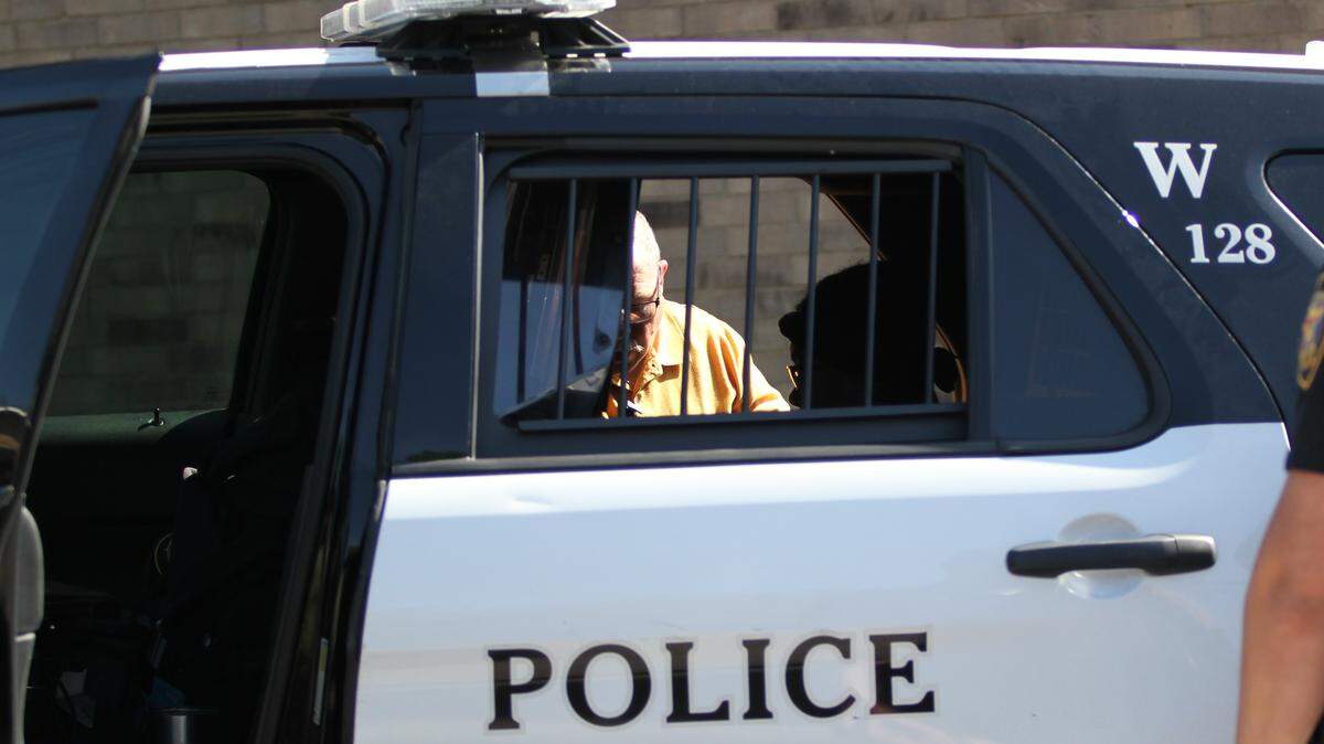 An unidentified woman who police say shot her husband after an argument over their tax return is interviewed by police in a patrol vehicle Thursday morning. Relatives said the woman will be taken to a women's shelter for her own safety.