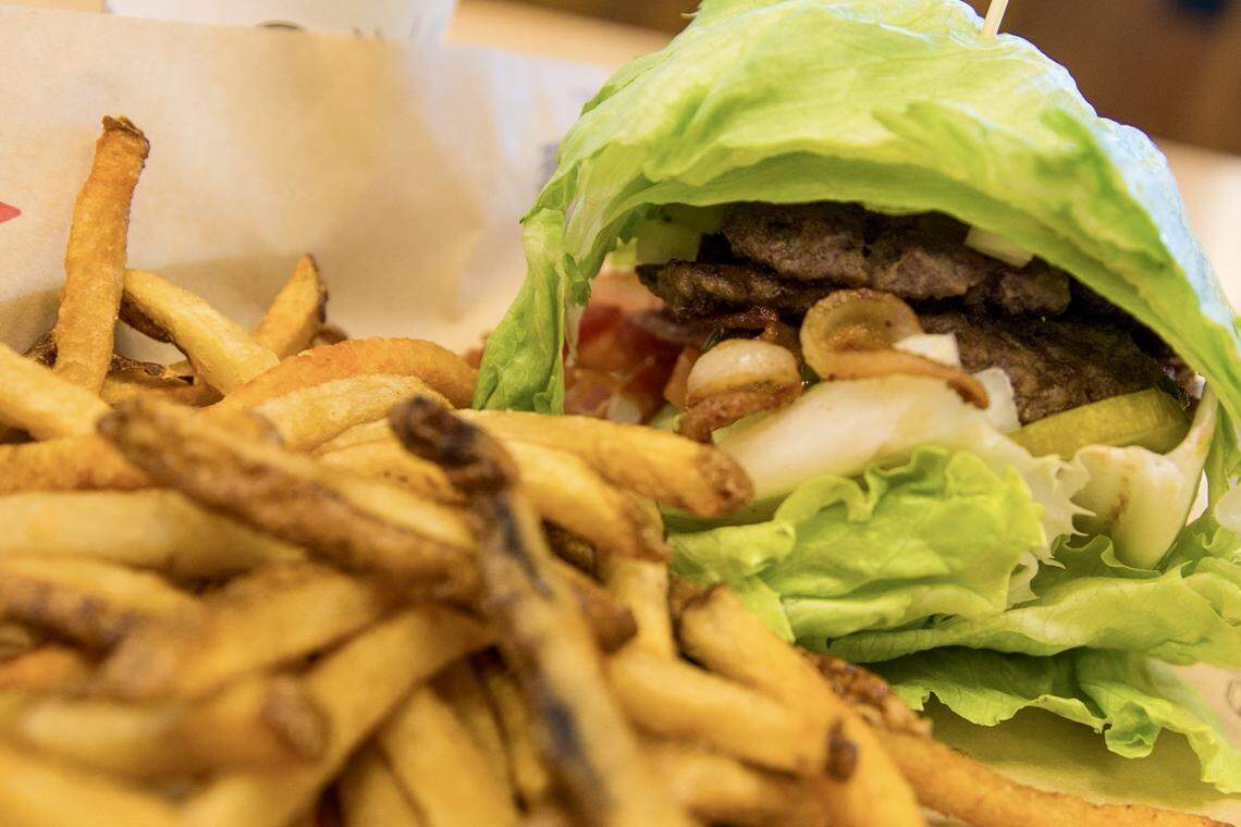A paleo burger with two Angus beef patties, smoked bacon, avocado slices, tomato, pickles, onion and mustard in between two fresh lettuce bundles, is shown at a Mooyah in El Paso, Texas, Jan. 7, 2022.