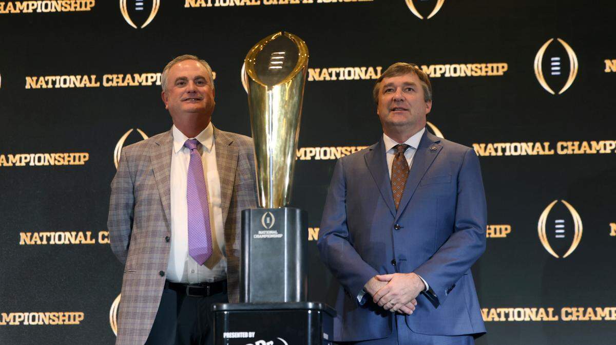 TCU head coach Sonny Dykes, left, and Georgia head coach Kirby Smart stand next to the National Championship Trophy during the head coaches news conference, Sunday.
