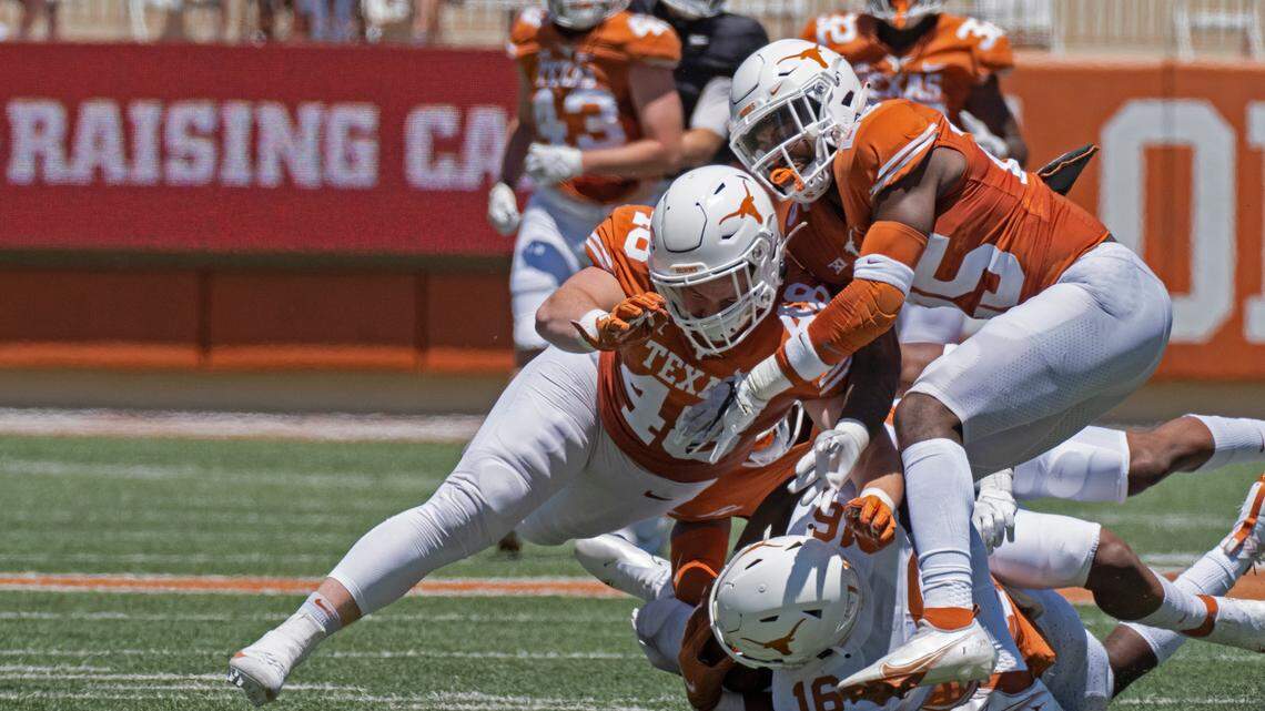 Texas defenders Jake Ehlinger, left, and B.J. Foster, right, tackle Kayvontay Dixon (16) during the first half of the Texas Orange and White Spring Scrimmage football game in Austin, Texas, Saturday, April 24, 2021. (AP Photo/Michael Thomas)