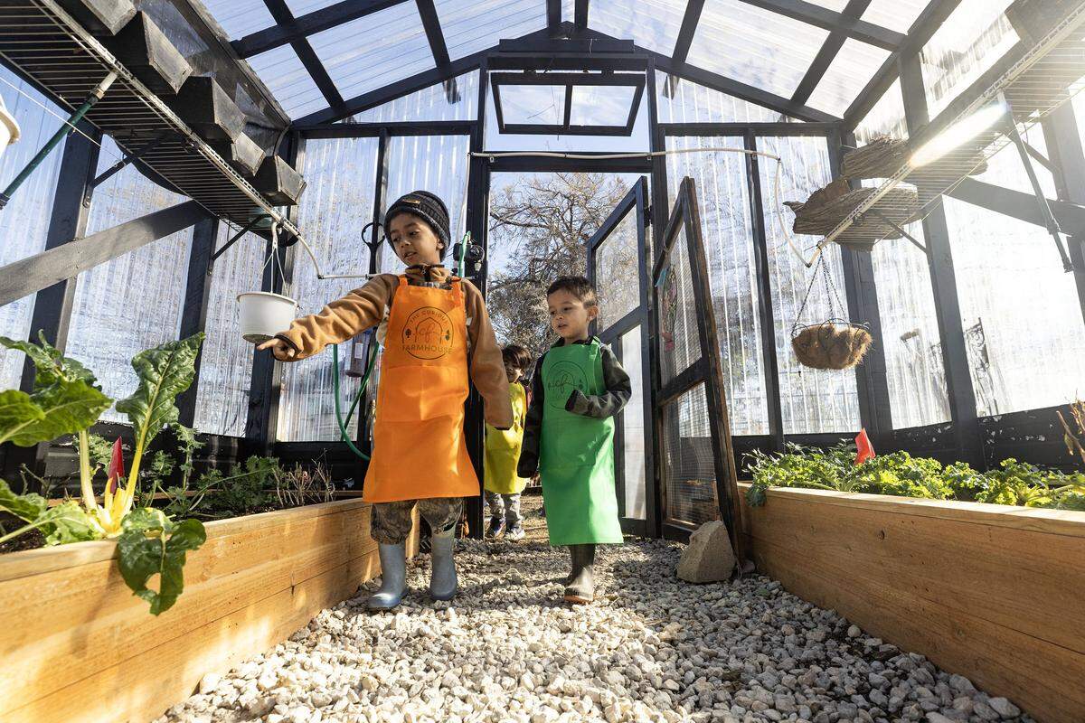 Brothers Gianluca, 6, and Julien Larrota, 4, enter the green house during class at the Curious Farm House in Godley on Wednesday, Dec. 10, 2025. The Curious Farmhouse is a nature-based, bilingual space where children learn farming, nutrition and hands-on skills through gardening.