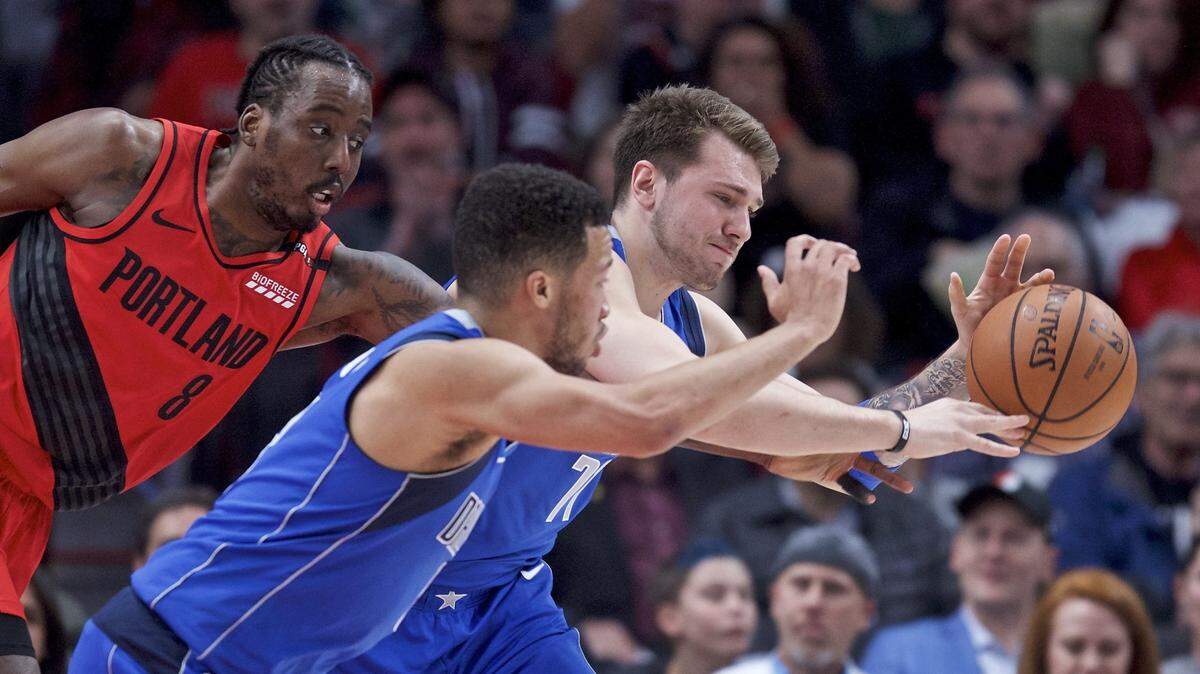Dallas Mavericks forward Luka Doncic, right, and guard Jalen Brunson, center, reach for a loose ball in front of Portland Trail Blazers forward Al-Farouq Aminu during the first half of an NBA basketball game in Portland, Ore., Wednesday, March 20, 2019. (AP Photo/Craig Mitchelldyer)