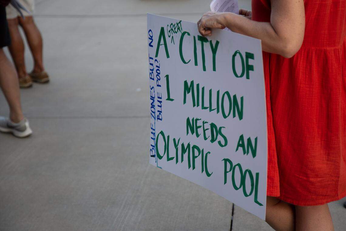 A woman holds up a sign at a community meeting to discuss replacing the Forest Park Pool.