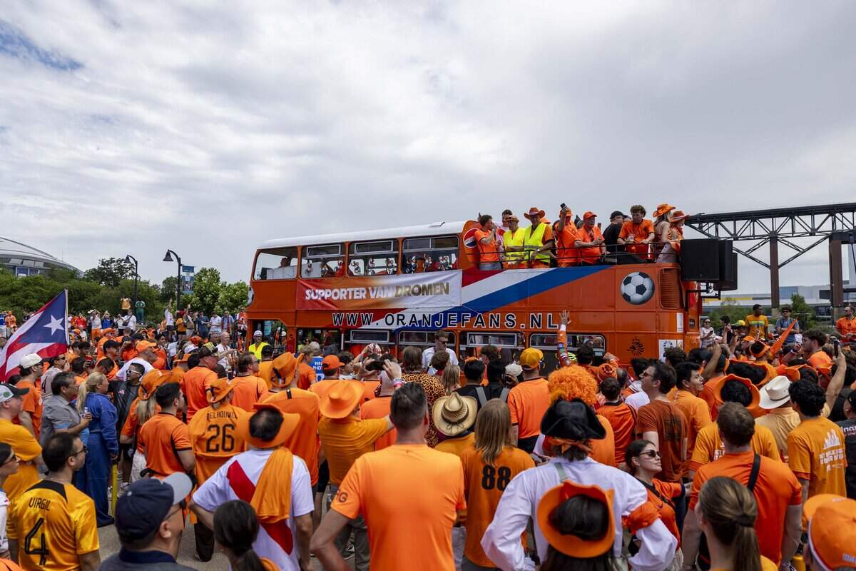 Netherlands soccer fans march to Dallas Stadium ahead of the FIFA World Cup match against Japan on Sunday, June 14, 2026 in Arlington, Texas. The famous double-decker Dutch Orange Bus, or De beroemde Oranjebus, is part of a Netherlands fan tradition bringing a sea of orange to the streets before major soccer matches.