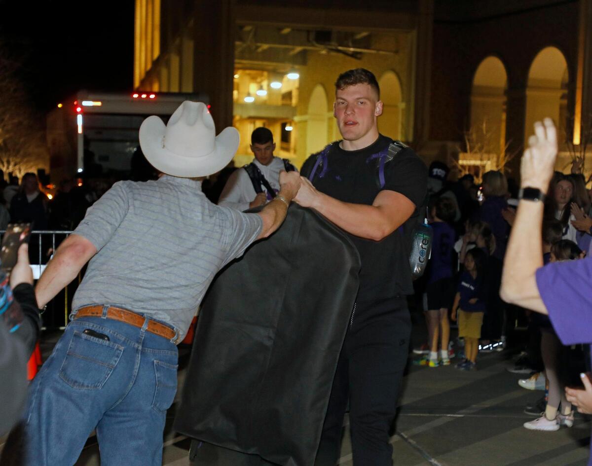 TCU Horned Frog tight end Alex Honig fist bumps a fan after returning home from the CFP national championship football game to the TCU Campus in Fort Worth, Texas, Tuesday, Jan. 10, 2023.