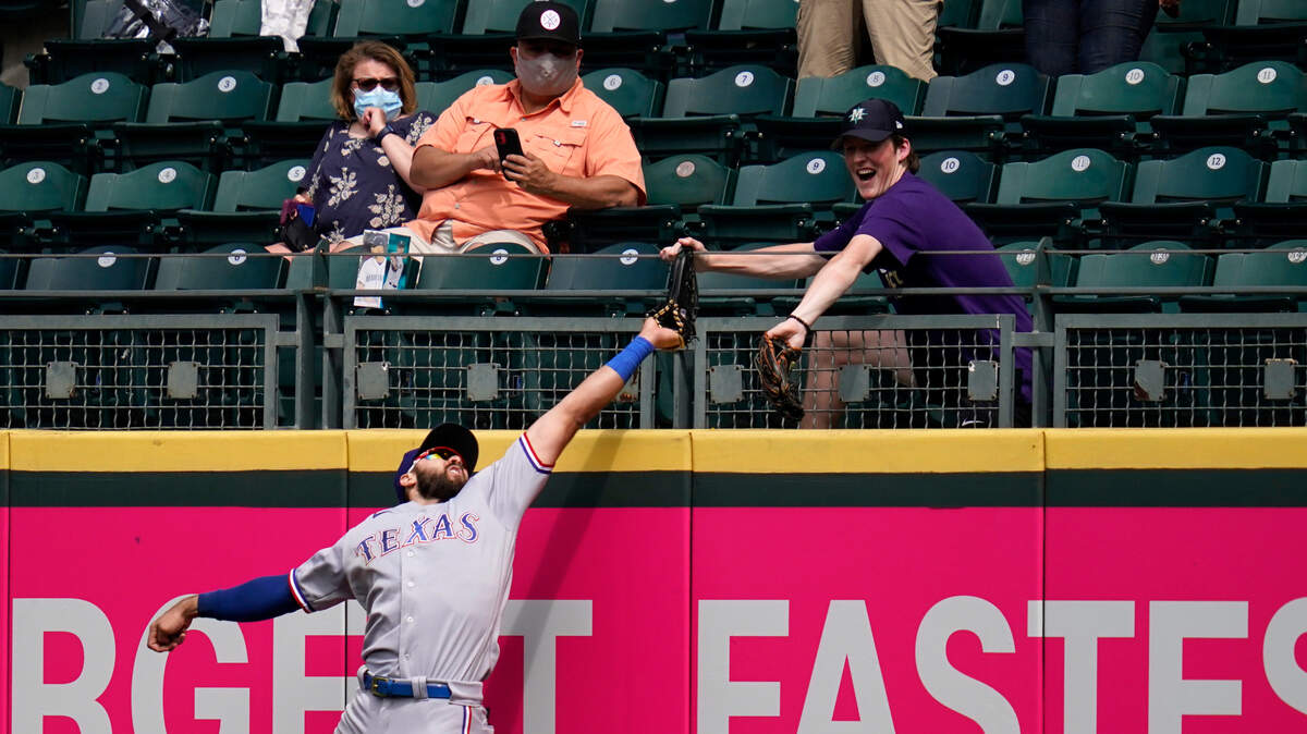 Texas Rangers right fielder Joey Gallo and a fan compete for the home run ball of Seattle Mariners’ Kyle Seager in the fifth inning Sunday. Gallo had a two-run homer in the 4-2 loss.